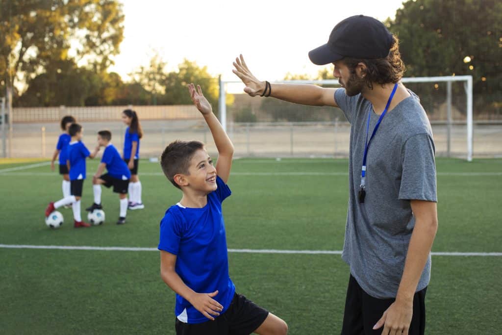 entrenador-futbol-felicitando-vista-lateral-nino-1024x683-1